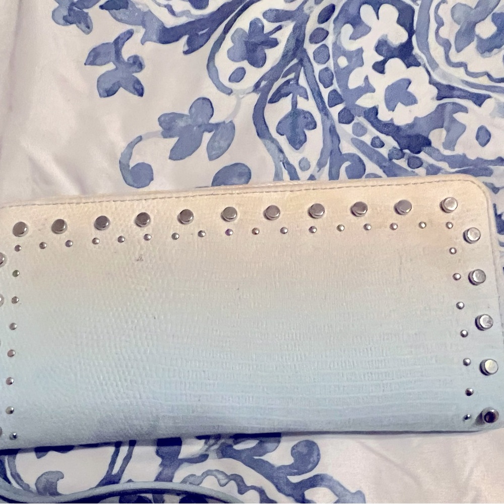 It a blue and white ombré wallet with silver studs going around the outer rim